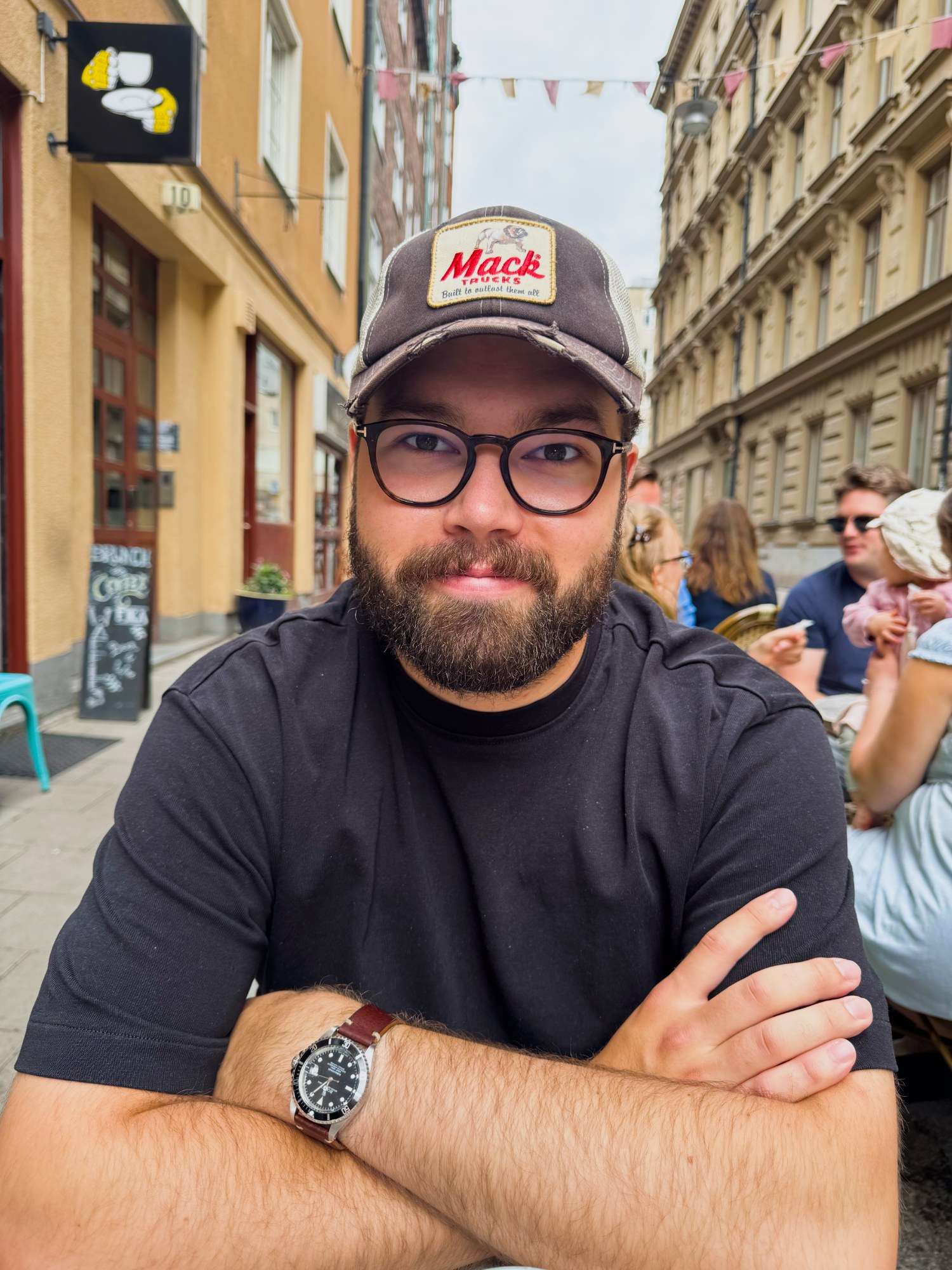 Portrait of Figge at an outdoor café table, arms crossed